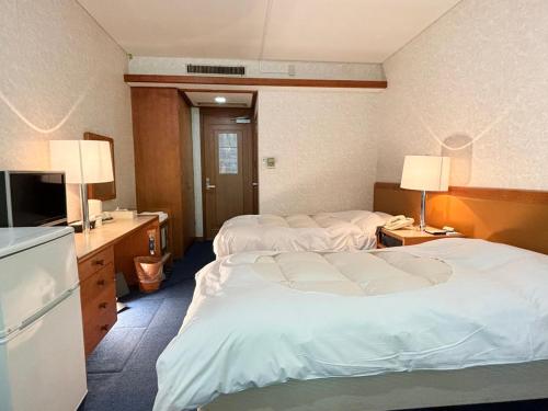 a hotel room with two beds and a television at Minami Hakone Villa in Kannami