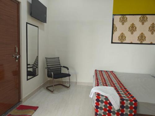 a bedroom with a bed and a chair and a mirror at Hari Sharnam Home Stay in Mathura