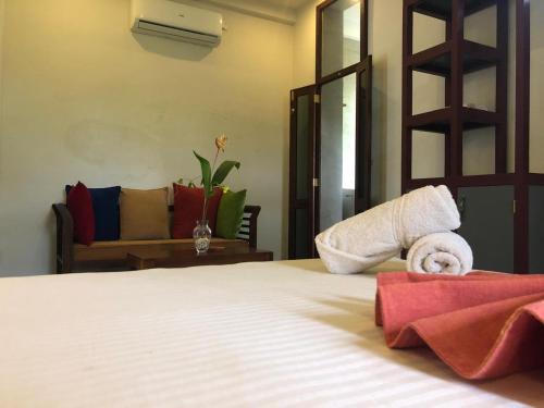 a bedroom with a bed with towels and a couch at Sithagi Villa Unawatuna in Unawatuna