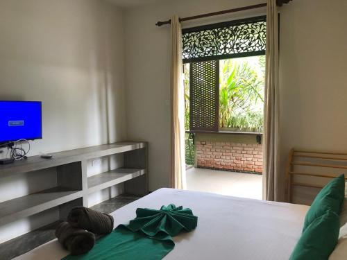a bedroom with a bed with a television and a window at Sithagi Villa Unawatuna in Unawatuna