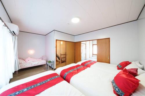 a bedroom with two beds with red pillows at oyadoya nagoya nakamura 地下鉄中村公園駅徒歩7分 最大8名 駐車場有り in Nagoya