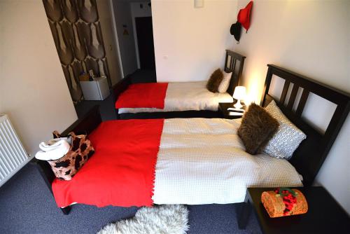a bedroom with two beds with red and white sheets at Hotel Biscuit in Cluj-Napoca