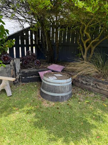 a firepit in a yard with a tree and a bench at Otaki Beach Guesthouse in Otaki Beach