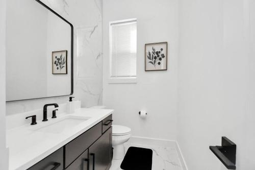 a bathroom with a sink and a toilet and a mirror at BlissHaven Luxe & Spacious in Downtown Houston with Soaking Tub ,Rooftop and free Parking in Houston
