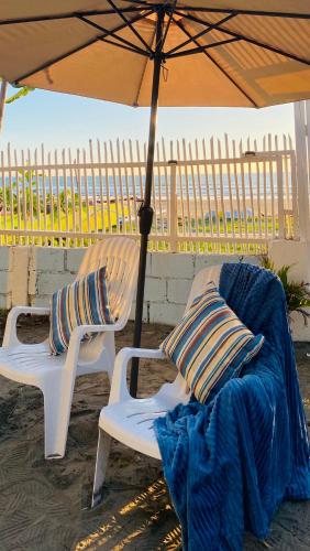 two chairs sitting under an umbrella on the beach at The Beach House at Elyu Exclusive Beach Front Villa in Bauang