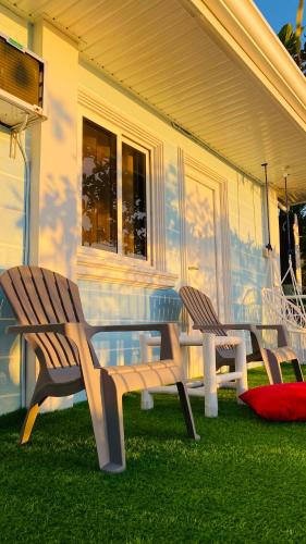 two wooden benches sitting in the grass in front of a house at The Beach House at Elyu Exclusive Beach Front Villa in Bauang