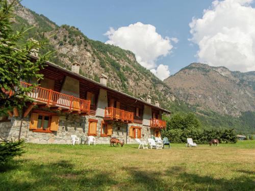 a building with chairs in a field next to a mountain at Belvilla by OYO GrBe Trilo in Antey-Saint-André