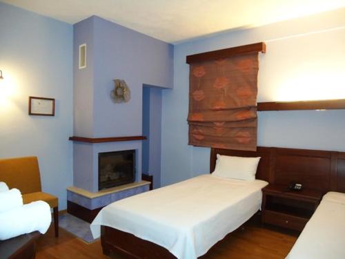 a blue room with two beds and a fireplace at Hotel Kokkinos Vrachos in Elati