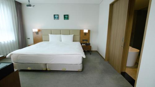 a bedroom with a large white bed in a room at Grabel Hotel Jeju in Jeju