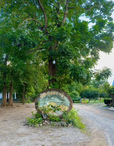 a sign sitting in front of a tree at บ้านไร่ดอกแก้ว in Chom Bung