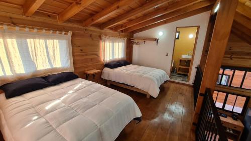 une chambre avec deux lits dans une cabane en rondins dans l'établissement Cabaña cerca de la naturaleza, a 20min de Valle, à Valle de Bravo