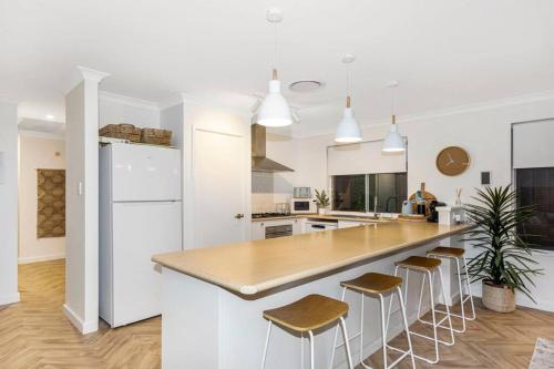 a white kitchen with a large island with bar stools at Town Central, walk to the beach in Busselton