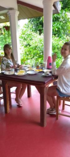 two people sitting at a table with plates of food at Sigiriya Moonlight Home in Sigiriya