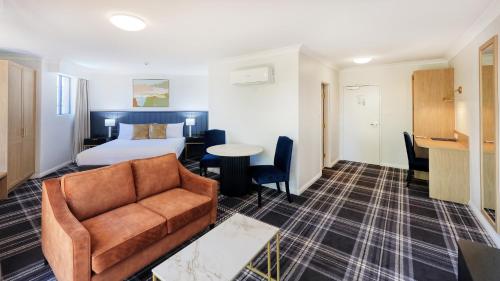 a hotel room with a bed and a couch and a table at Dubbo RSL Club Motel in Dubbo