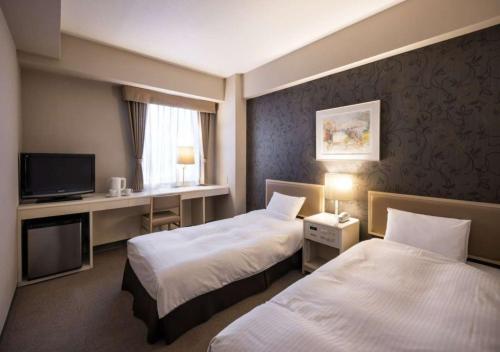 a hotel room with two beds and a television at Business Inn Norte in Sapporo