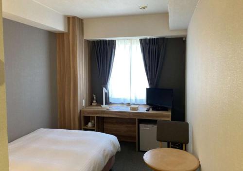 a bedroom with a bed and a desk and a window at Business Inn Norte in Sapporo