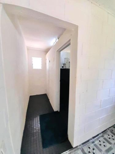 a hallway with a white brick wall and a black refrigerator at Double Twin Private Room - Tonga Horizon Cottage in Nuku‘alofa