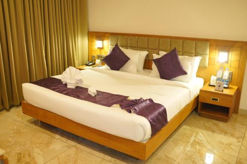 a hotel room with a large bed with purple pillows at Hotel Devalokam in Trittāla