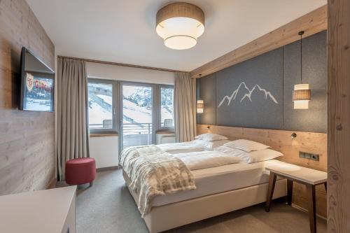 a bedroom with a bed and a wall with mountains at Hotel Gurglhof Superior in Obergurgl