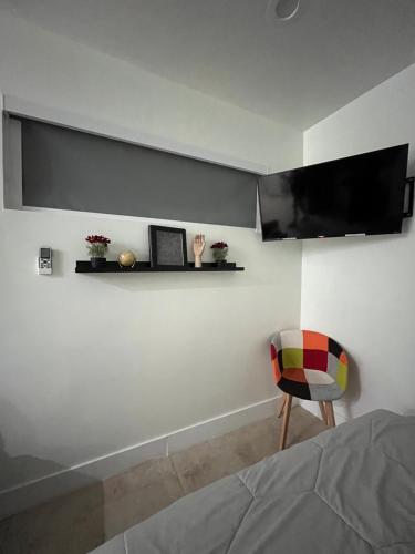 a bedroom with a chair and a tv on the wall at Luna y Sol Calle 8 in Miami