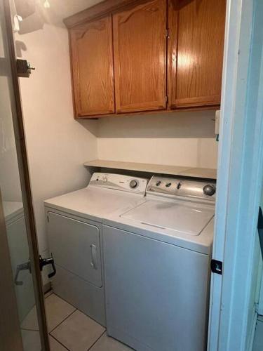 a kitchen with a washing machine and wooden cabinets at Casa Colibrí in Harlingen