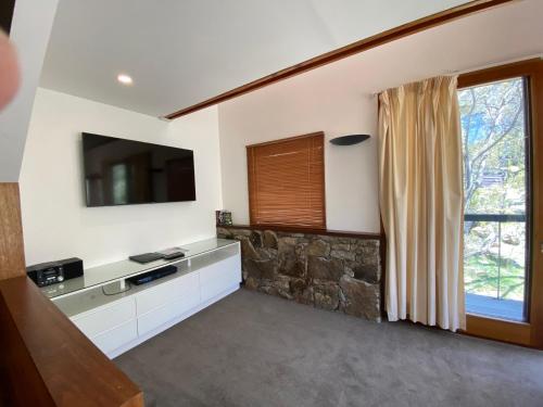 a living room with a tv and a window at Ramshead Creek 3 - Thredbo in Thredbo
