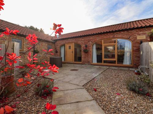 a brick house with a patio with red flowers at Kingfisher Corner in Great Driffield