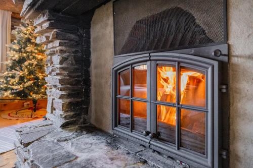 a fireplace with a christmas tree in the background at The Haven of Riverside - Villa Sieripirtti in Rovaniemi