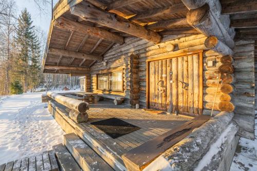 a log cabin with a deck in the snow at The Haven of Riverside - Villa Sieripirtti in Rovaniemi