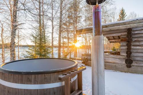 a jacuzzi tub in the snow next to a cabin at The Haven of Riverside - Villa Sieripirtti in Rovaniemi