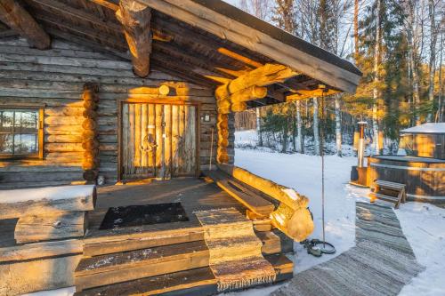 a log cabin with a porch in the snow at The Haven of Riverside - Villa Sieripirtti in Rovaniemi