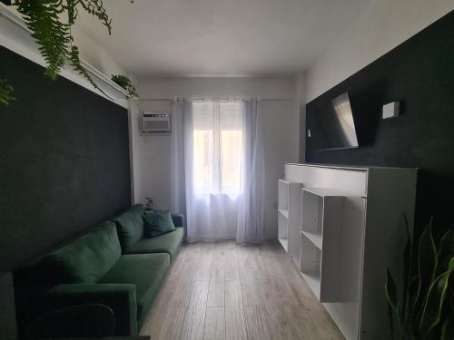 uma sala de estar com um sofá verde e uma janela em Studio Praia de Botafogo no Rio de Janeiro
