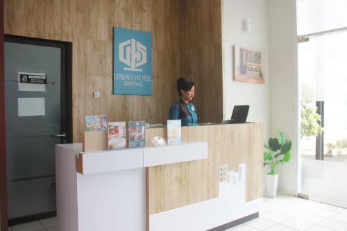 a woman sitting at a reception desk in a office at Urban Hotel Serpong in Banten