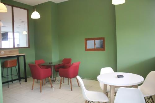a waiting room with red chairs and tables and a green wall at Urban Hotel Serpong in Banten