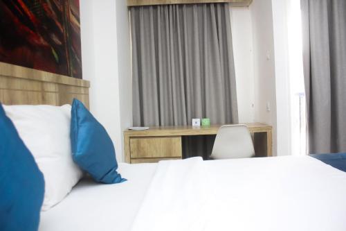 a bedroom with a bed with blue pillows and a desk at Urban Hotel Serpong in Banten