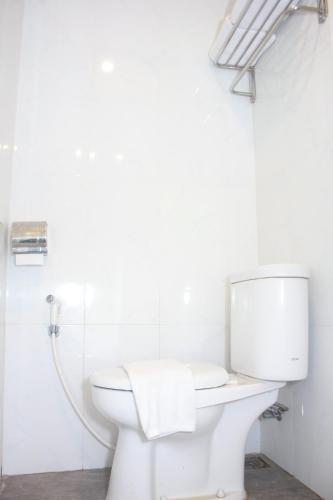 a white bathroom with a toilet and a shower at Urban Hotel Serpong in Banten