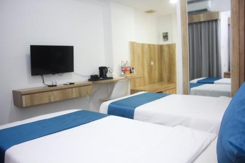 a hotel room with two beds and a flat screen tv at Urban Hotel Serpong in Banten