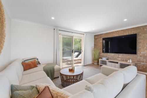 a living room with white furniture and a brick wall at The Beach House 64 Neighbour Ave Goolwa Beach - No Linen Included in Goolwa