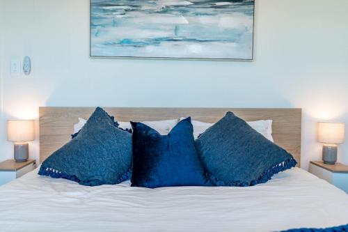 a bed with blue pillows on top of it at The Beach House 64 Neighbour Ave Goolwa Beach - No Linen Included in Goolwa