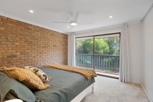 a bedroom with a brick wall and a large window at The Beach House 64 Neighbour Ave Goolwa Beach - No Linen Included in Goolwa