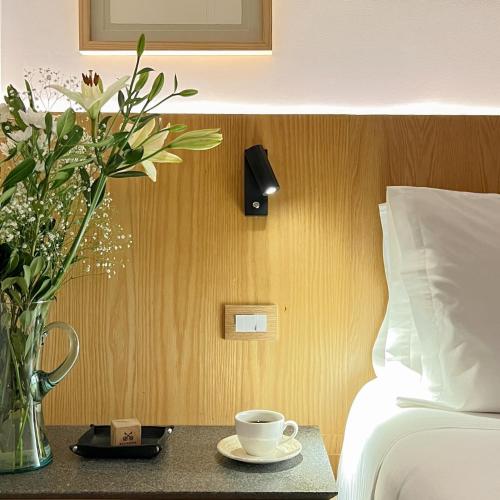 a vase of flowers on a table next to a bed at Reforma Guest House in Mexico City