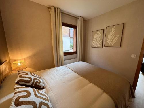 a bedroom with a large bed with a window at T2 design et cosy à La Clusaz avec terrasse sud et garage privé - FR-1-459-235 in La Clusaz