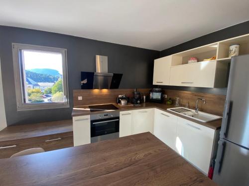 une cuisine avec des armoires blanches, un évier et une fenêtre dans l'établissement Appartement 4 étoiles à Villard-de-Lans, 2 chambres, terrasse sud, parking et navette ski - FR-1-737-91, à Villard-de-Lans