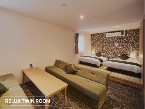 a living room with a couch and two beds at Sakura Garden Hotel in Osaka