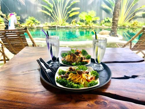a table with a plate of food and two glasses of water at Cóc Retreat Mỹ Tho City in My Tho