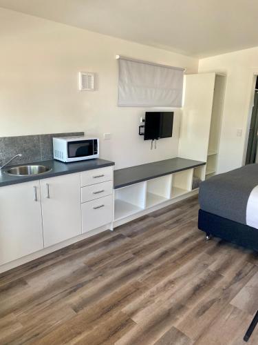 Habitación con cocina con cama y microondas. en Bacchus Marsh Caravan Park, en Bacchus Marsh