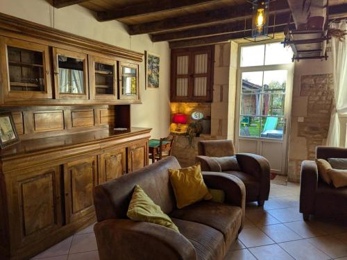 un salon avec un canapé, des chaises et une fenêtre dans l'établissement Maison de caractère avec jardin, terrasse et équipements famille - Proche plan d'eau et forêt - FR-1-653-47, à Villefagnan