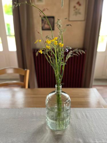 a glass vase with flowers in it on a table at Moulin de Maupoy in Saint-Symphorien-de-Marmagne