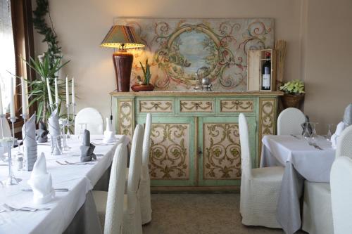 a dining room with white tables and chairs and a dresser at Aurora in Castione della Presolana