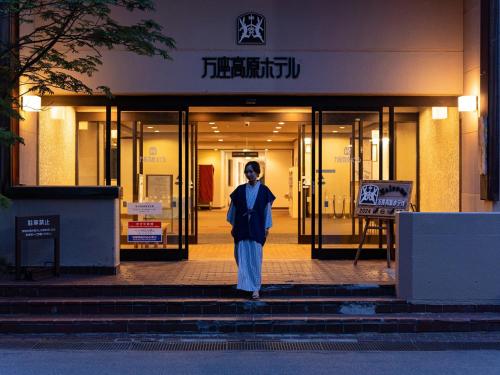a man is standing in front of a building at Manza Kogen Hotel in Tsumagoi